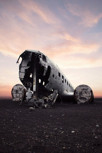 Abandoned airplane on runway against sky during sunset