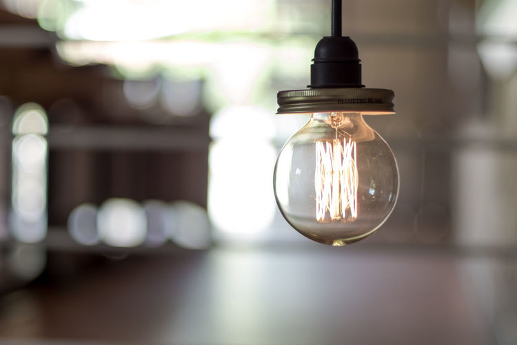 Close-up of illuminated light bulb hanging indoors