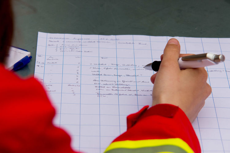 Cropped image of person writing on paper at table