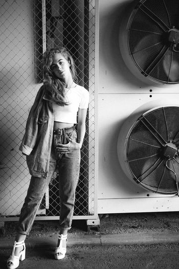 Portrait of teenage girl standing against exhaust fans