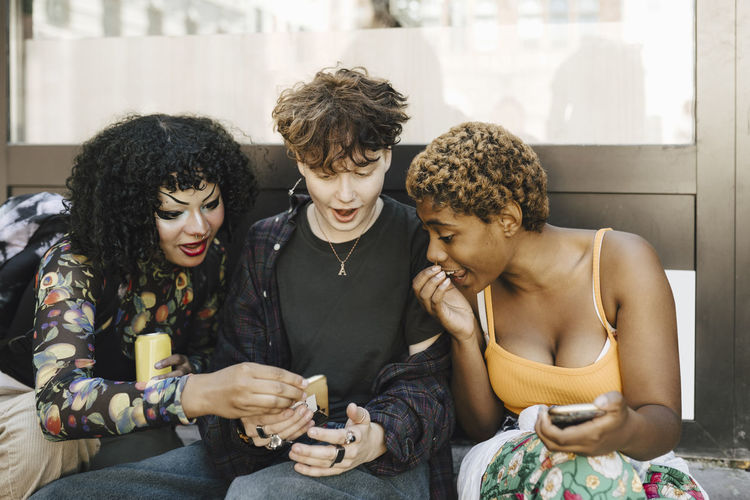 Teenage boy sharing smart phone with shocked friends
