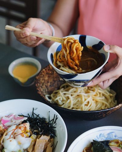 Midsection of woman having tsukemen with cheese and curry at restaurant