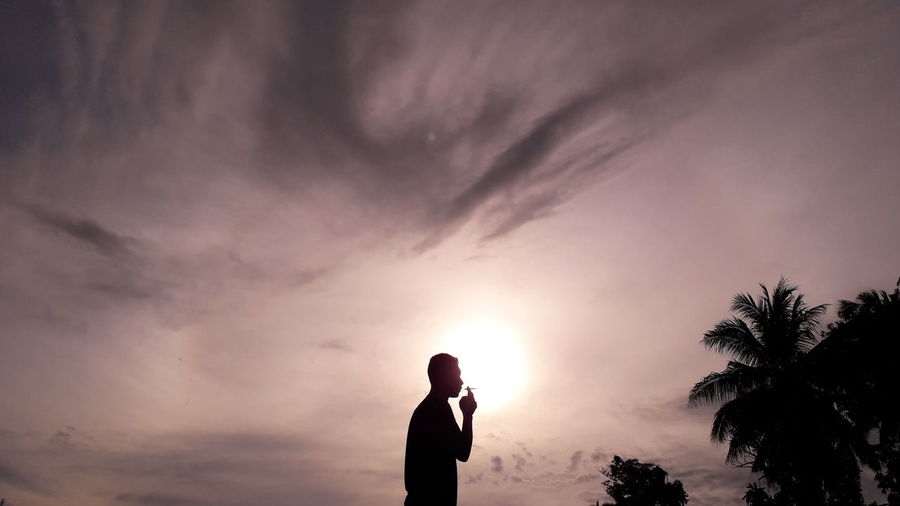 Silhouette man standing against sky during sunset