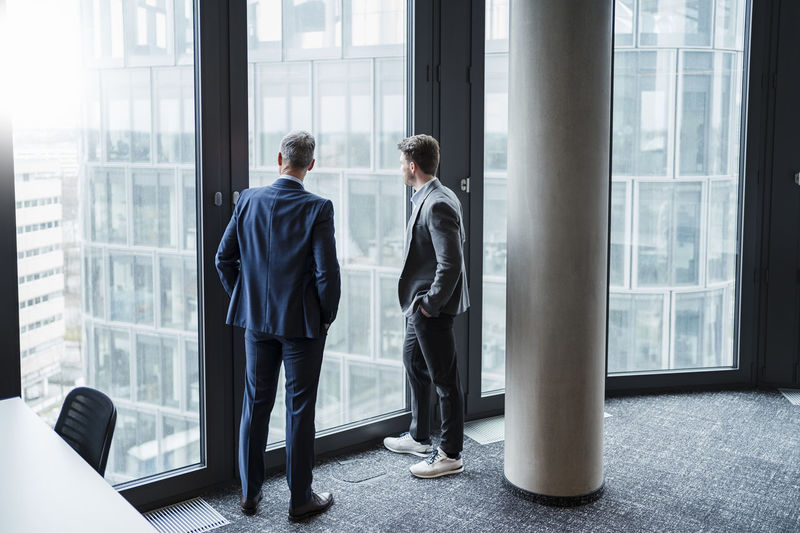 Businessman and entrepreneur looking through window in office