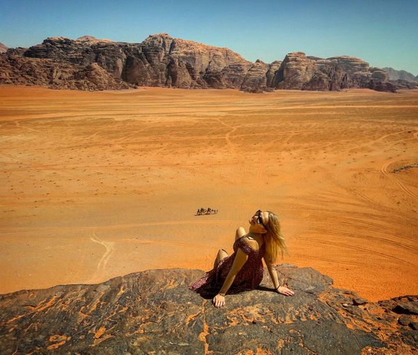High angle view of woman sitting on rock at desert