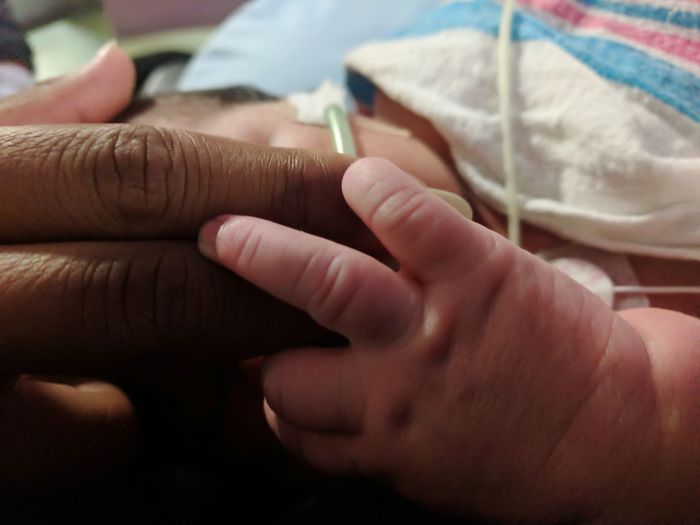 Close-up of baby and parents hand in hospital