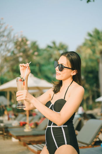 Midsection of woman holding sunglasses standing outdoors