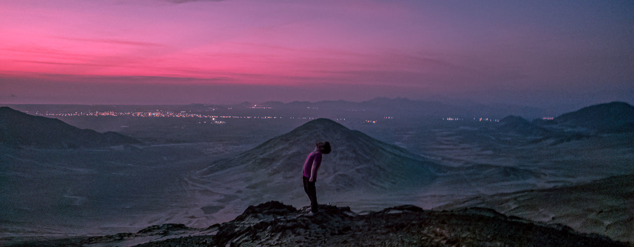 Man standing on mountain against sky during sunset