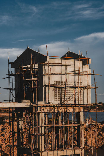 Construction site by abandoned building against sky