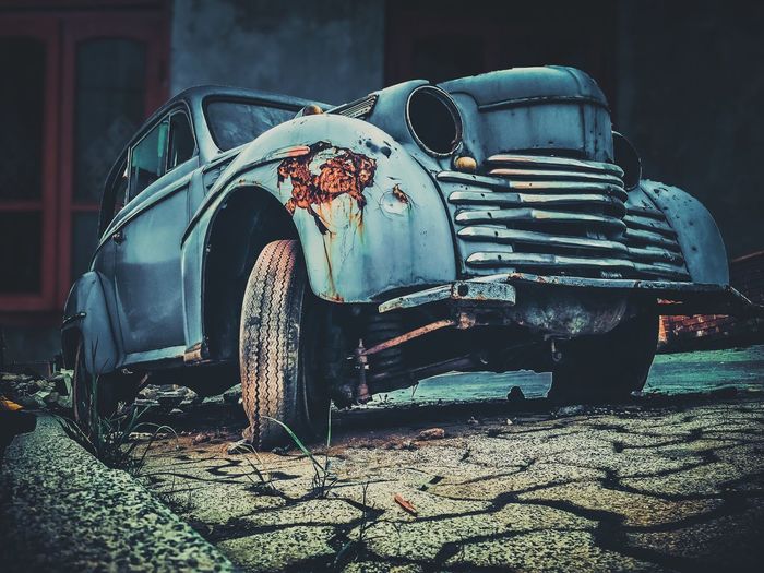 Low angle view of abandoned vintage car on paving street