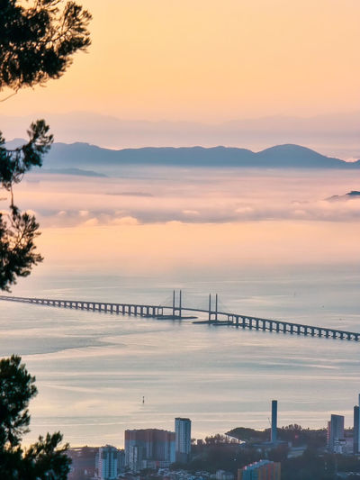 Scenic view of sea and bridge against sky during sunrise