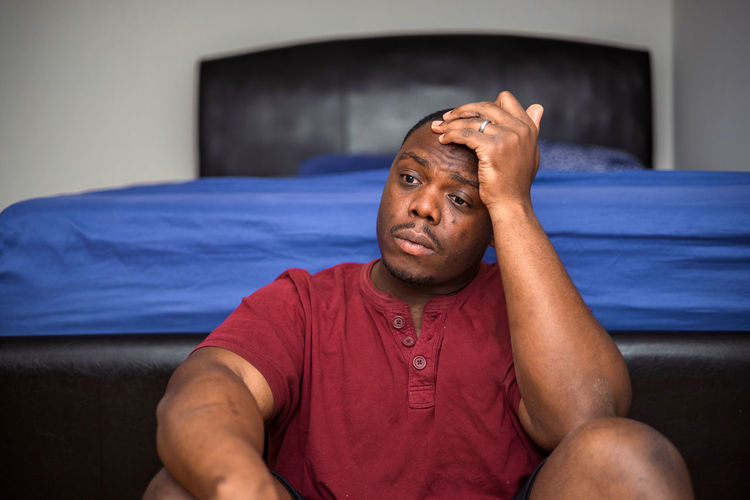 Depressed and anxious african american or black man sitting at home
