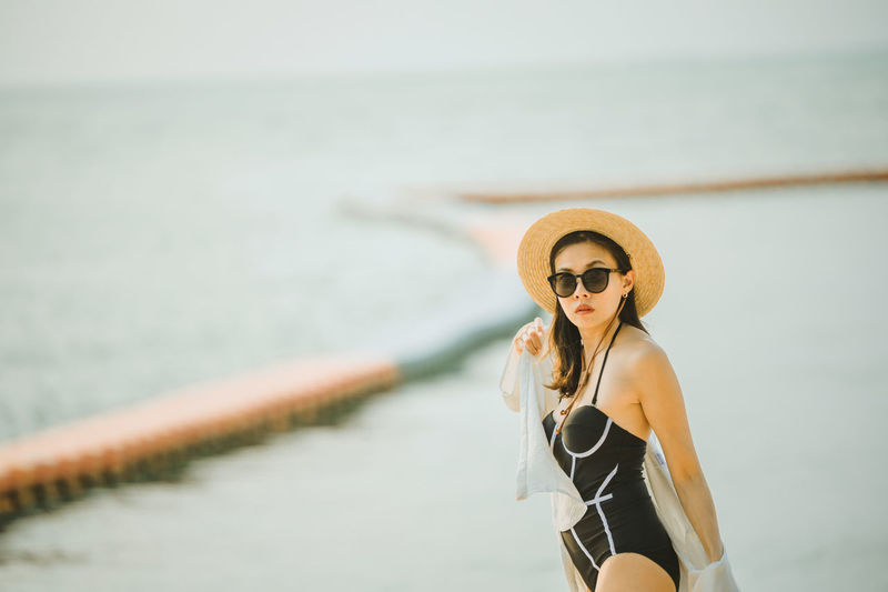 Woman wearing sunglasses standing against sea