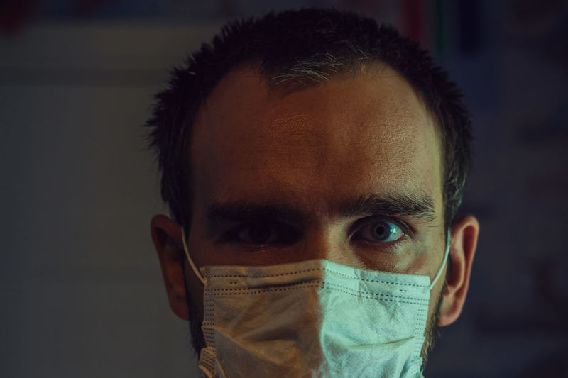 The face of a white man wearing a medical mask in close-up person