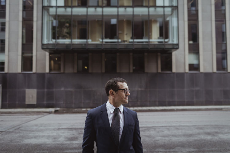 Businessman wearing eyeglasses while looking away in city