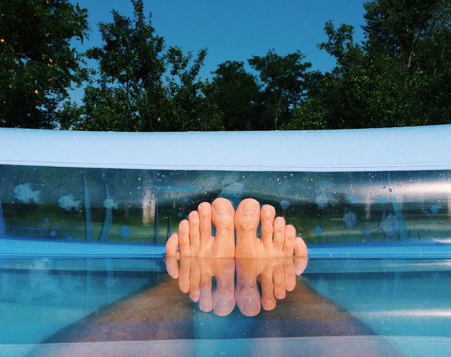 Low section of man legs in wading pool against sky