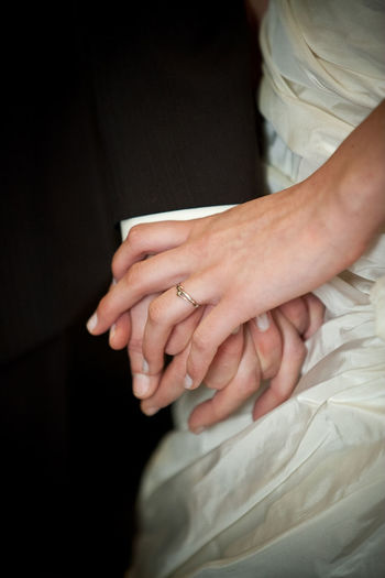 Midsection of newly wed couple holding hands