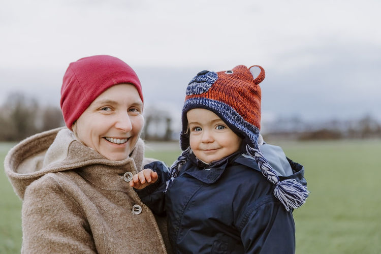 Portrait of smiling woman with boy standing at park