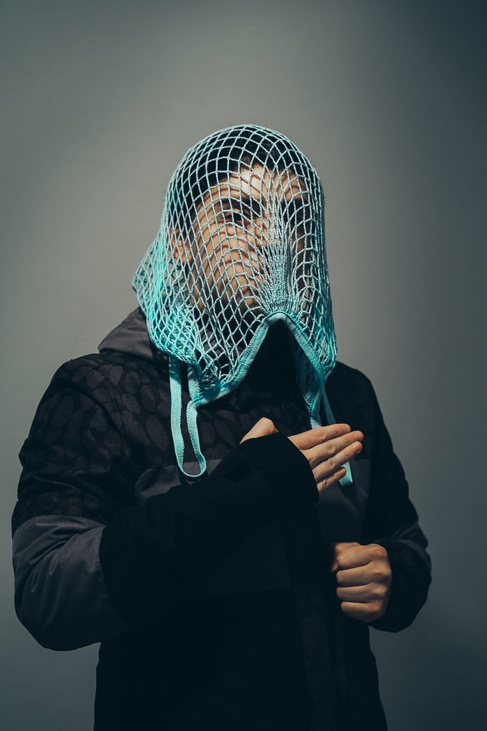 Man covered with net against gray background