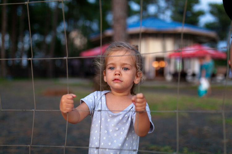 Portrait of cute girl standing by fence