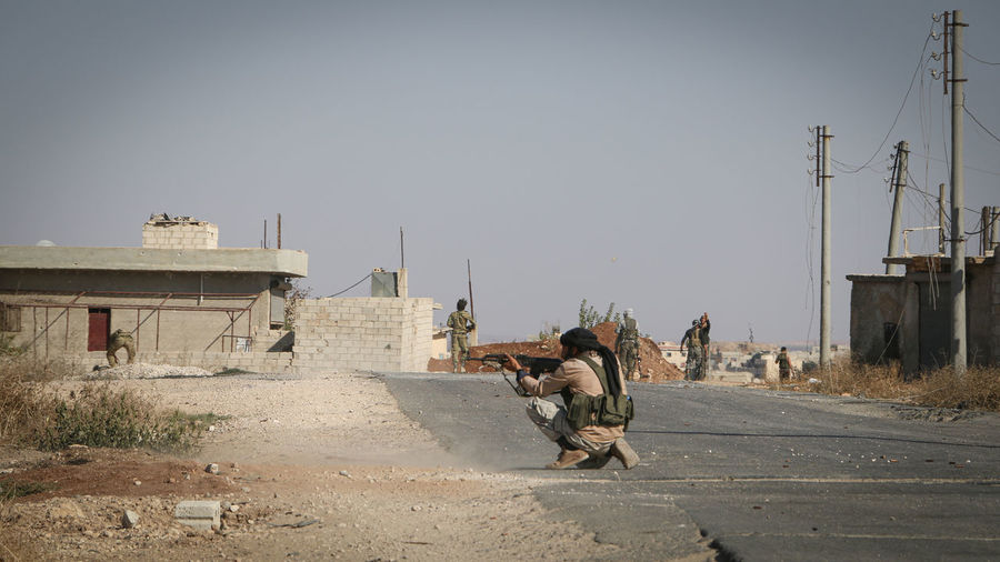 Man aiming gun while crouching on road