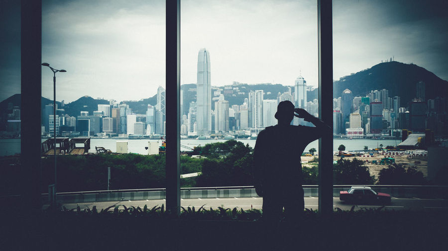 Silhouette man standing by window against victoria harbour