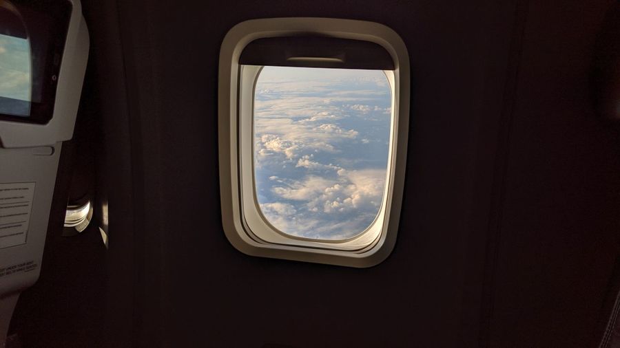 Reflection of clouds in sky seen through airplane window