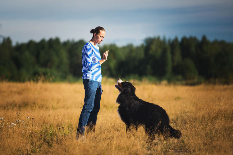 Side view of man training with dog on grassy land