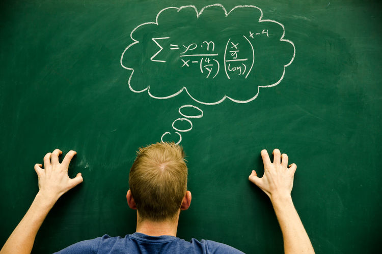 Man gesturing with mathematical formula on blackboard