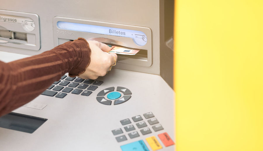 Close-up view of a hand withdrawing money from an atm, concept of cash, currency exchange.