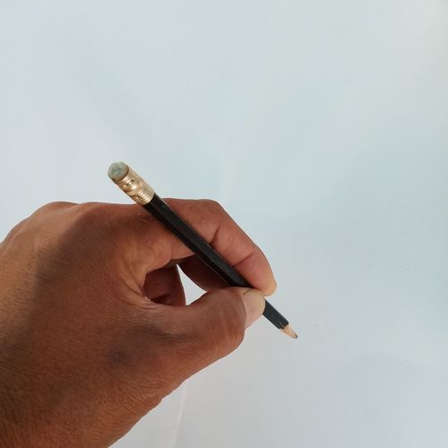 Close-up of hand holding cigarette against white background