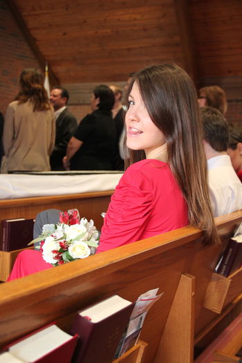 Portrait of young woman sticking out tongue while sitting in church
