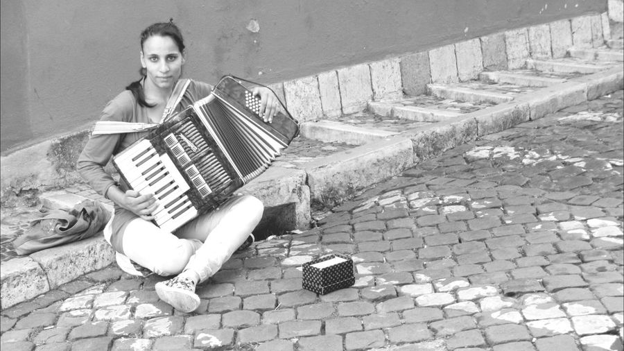 Portrait of young woman playing accordion on street