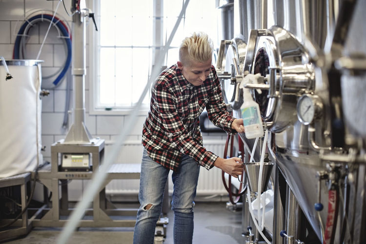 Female manager working by storage tank at brewery