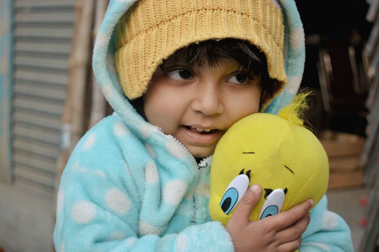 Close-up of girl in warm clothing holding stuffed toy outdoors