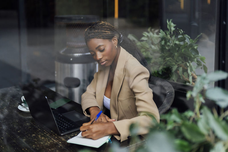 Young businesswoman making notes at cafeteria