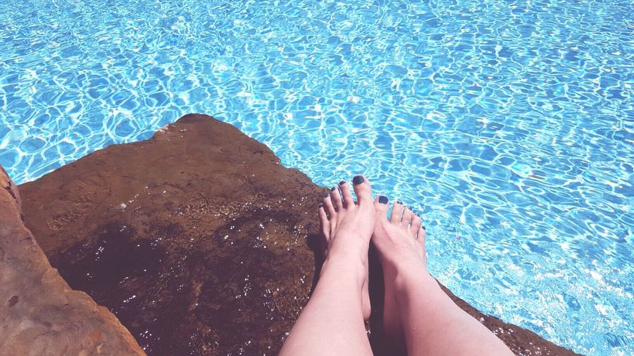 Low section of woman feet by swimming pool