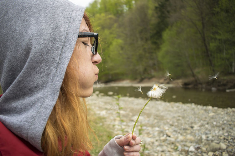 Close-up of woman blowing dandelion seeds