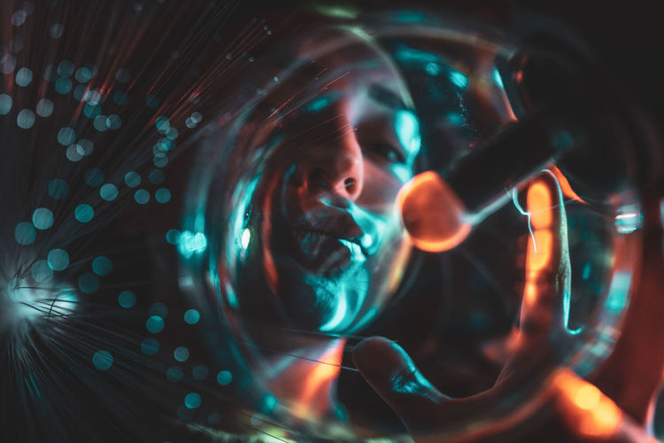 Digital composite image of woman and plasma ball with fiber optics