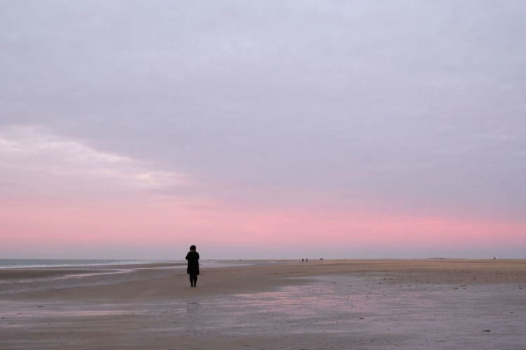 Distant woman at beach during sunset