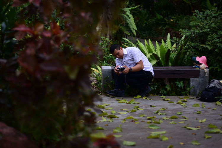 Full length of man sitting on mobile phone