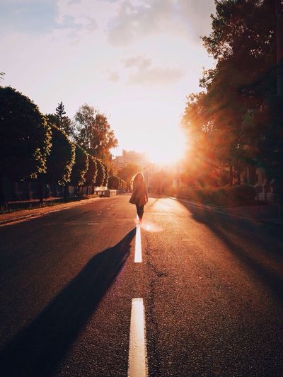 Man walking on road against sky during sunset