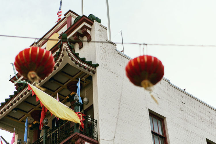Low angle view of red lanterns hanging by building against sky