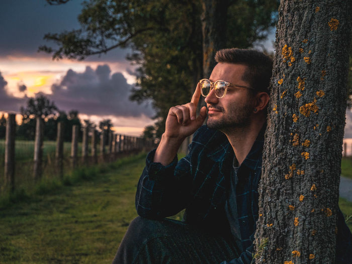 Portrait of young man on tree trunk