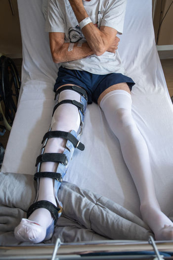 A man with a broken leg in an orthese in bed in a clinic after an accident,
