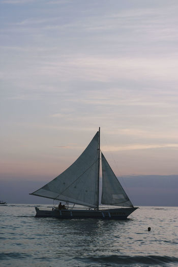 Sailboat sailing on sea against sky during sunset