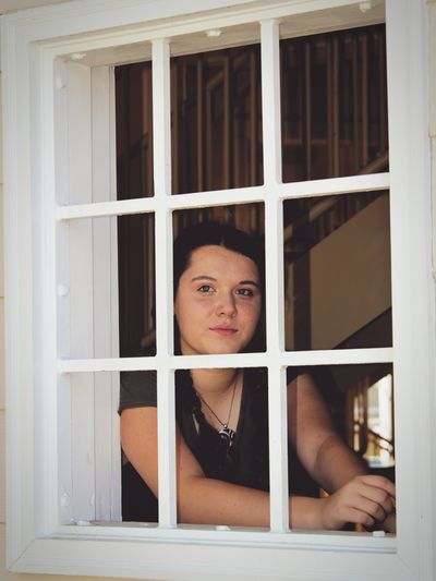 Thoughtful young woman seen through glass window