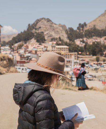 Side view of woman wearing hat reading book outdoors