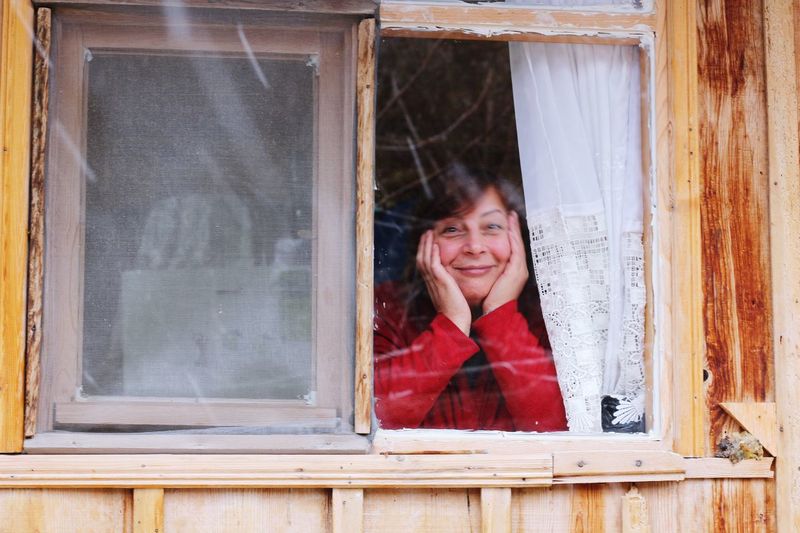 Portrait of smiling young woman looking through window