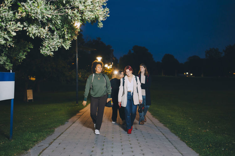 Happy male and female friends walking in campus at night